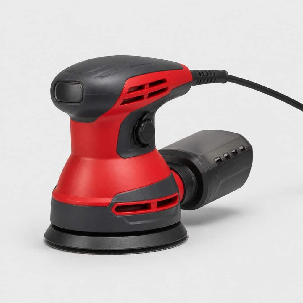 Ponceuse excentrique filaire rouge et graphite avec câble sur un établi