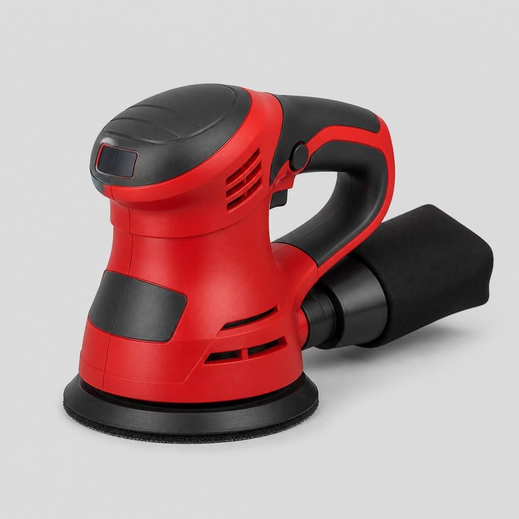 Ponceuse excentrique de finition rouge et graphite sur un plan de travail